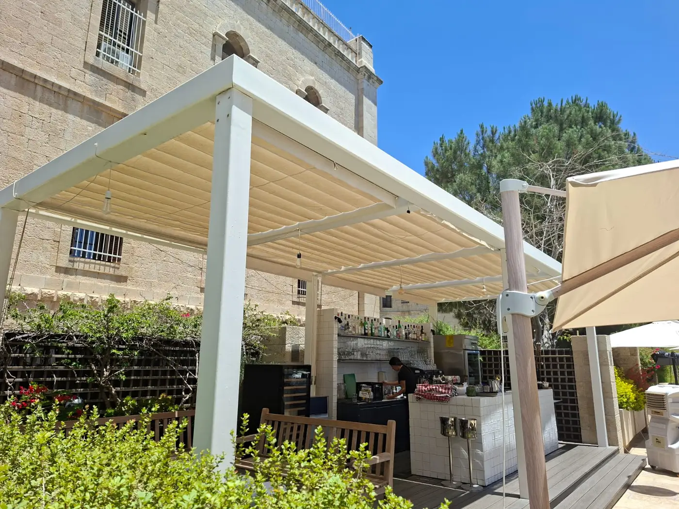 פרגולה עם כיסוי בד נפתח מעל בר בגינה